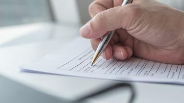 Hand holding pen and filling in form