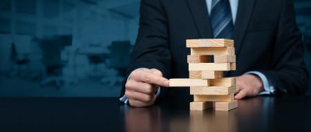 Man wearing a suit playing the wooden block game Jenga