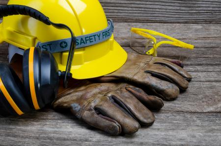 Hardhat with work gloves, headphones, and safety glasses